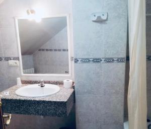 une salle de bain avec un lavabo et une douche avec un miroir dans l'établissement Hostal Libertad, à Villadangos del Páramo