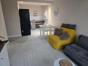een woonkamer met een gele bank en een tafel bij Apartment Cherry in Gryfice +9 foto's