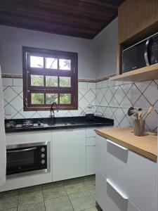 een keuken met witte apparatuur en een raam bij Armação - Florianópolis - 2 quartos de casal in Florianópolis