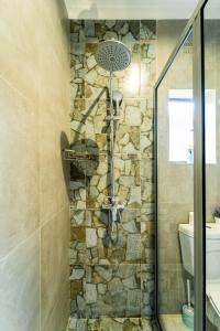 una doccia in un bagno con un muro in pietra di KhayaLethu Vic Falls 2 a Victoria Falls Altre 27 foto