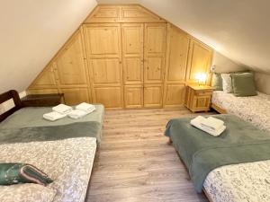 een kamer met 2 bedden en een houten muur bij Przystanek Rabka - Domek całoroczny in Rabka