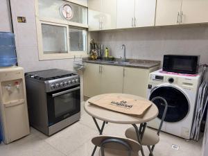 een keuken met een fornuis, een wastafel en een tafel bij Shared Apartment Room with Private Washroom in Sharjah