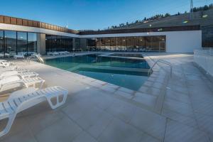 une piscine avec des chaises longues et un bâtiment dans l'établissement Skigyimes Hotel, à Lunca de Sus