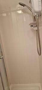 een douche in een badkamer met een witte muur bij Lily Hotel Blackpool in Blackpool