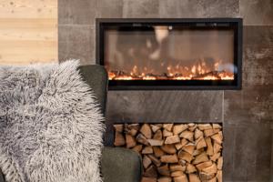 een open haard met een stapel brandhout en een stoel bij Gaia Residence Hotel in Mezzana