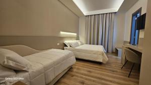 ein Hotelzimmer mit zwei Betten und einem Fernseher in der Unterkunft Hotel del Sole-Aversa in Aversa