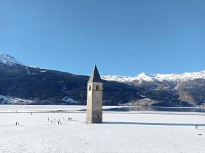 een kerk op een strand met besneeuwde bergen bij Panorama Wildgrat in Wenns +25 foto's