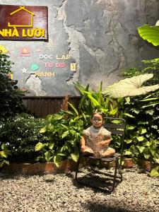 a young girl sitting in a chair in a garden at Nhà Lười Homestay in Hue