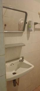 un lavandino bianco con uno specchio su una parete di D Love Gueshouse a Ranong