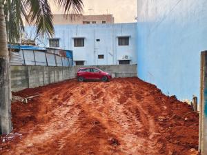 une voiture rouge garée sur un chemin de terre à côté d'un bâtiment dans l'établissement skyway Rooms, à Pondichéry