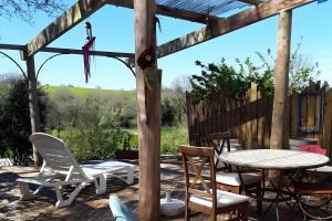 een houten pergola met een tafel en stoelen op een patio bij Au restalèz in Trémargat