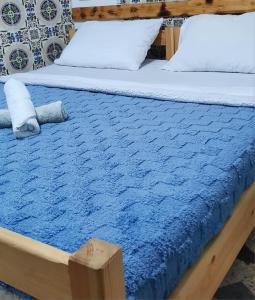 een bed met een blauwe deken en kussens erop bij Habibi Hostel in Taghazout