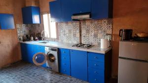 a kitchen with blue cabinets and a washing machine at Atlas lodge in Sidi Hassaïn