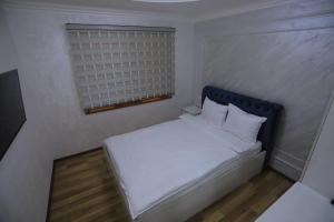 een kleine slaapkamer met een wit bed en een raam bij ASR HOSTEl in Andizhan