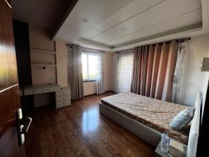 une chambre avec un lit et une fenêtre avec des rideaux dans l'établissement Triluna Apartments, à Pātan 3 autres photos