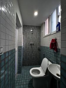 une salle de bains avec douche, toilettes et lavabo dans l'établissement Triluna Apartments, à Pātan