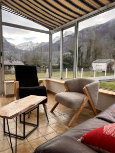 a living room with a couch and chairs and a large window at Chez Négus in Laruns