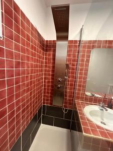 a red tiled bathroom with a sink and a mirror at Chez Négus in Laruns