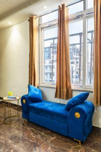 a blue couch in a room with windows at Bnb Sakura , Golf Course Road in Gurgaon