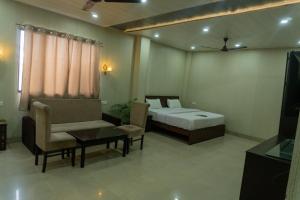 een slaapkamer met een bed, een bank en een tv bij Krazy Hotel in Haldwani