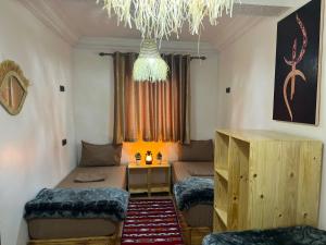 een kamer met 2 bedden, een tafel en een kroonluchter bij tawja surf house in Taghazout