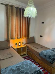 een kamer met 2 bedden en een kroonluchter bij tawja surf house in Taghazout
