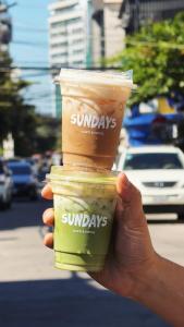 a person holding two cups of coffee in their hand at Sundays Boutique Eco Hotel in Phnom Penh