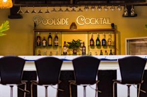 a bar with black chairs in front of a shelf of bottles at De Arya Angkor Resort in Siem Reap
