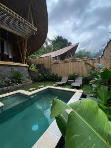 une piscine dans un jardin avec une maison dans l'établissement Hidden Bamboo Village, à Selat