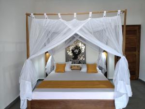 ein Schlafzimmer mit einem Himmelbett mit weißen Vorhängen in der Unterkunft Mangrov'Evasion in Mahajanga