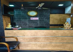 a counter with a clock on a wall with chairs at Geetha Residency in Anantapur