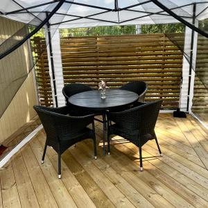 une table et des chaises noires sur une terrasse en bois dans l'établissement Karamellgårdens stuga, à Herräng