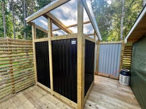 un porche en bois avec un portail noir sur une terrasse en bois dans l'établissement Karamellgårdens stuga, à Herräng 3 autres photos