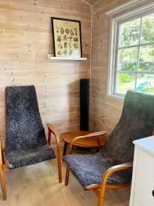 - 2 chaises et une table dans une chambre dotée de murs en bois dans l'établissement Karamellgårdens stuga, à Herräng