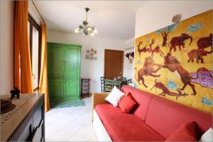 a living room with a red couch and a painting of horses at Senia in San Vito lo Capo