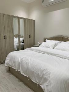 een slaapkamer met een groot wit bed en een spiegel bij SUKN Qiddiya- Al Muzahimiyah in Riyad