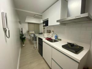 a white kitchen with a sink and a refrigerator at Azure North - Aurora Sky in San Fernando