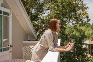 une femme debout sur une terrasse couverte tenant un verre de vin dans l'établissement Story Haus, à Stellenbosch