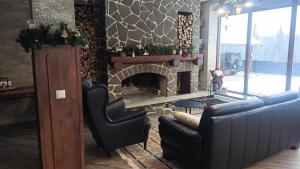 a living room with a fireplace with a couch and a chair at UnderДіл in Krivopolʼye