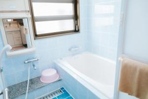 a blue bathroom with a tub and a window at Nagoya in Nakijin