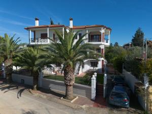 a white house with palm trees in front of it at Villa Palmera 100m from the beach in Nikiti