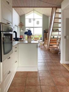 eine Küche mit weißen Schränken und einem Fliesenboden in der Unterkunft Summer House With Panoramic View Near Doverodde in Doverodde + 21 Fotos