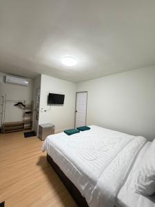 une chambre avec un lit blanc et une télévision à écran plat dans l'établissement Greenview Room and Restaurant, 