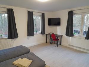 een woonkamer met een bank, een bureau en ramen bij Boardinghaus Waldesruh in Lohne