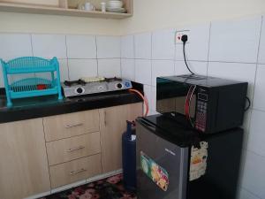 a kitchen with a microwave on top of a refrigerator at Beijing Nest in Syokimau