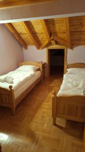 two beds in a room with wooden floors at Kuća za odmor Diva Blidinje, Risovac 455 in Blidinje
