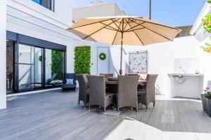 un patio con tavolo, sedie e ombrellone di LUX House a Ponta Delgada