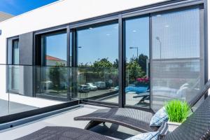 un balcone con finestre in vetro e due sedie di LUX House a Ponta Delgada