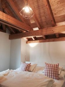 Schlafzimmer mit einem weißen Bett und Holzdecken in der Unterkunft Ferienhaus Grüner Heinrich in Andermatt