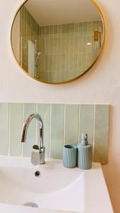 Ein Spiegel über einem Waschbecken mit zwei Tassen darauf. in der Unterkunft Dréo - Spacieux avec terrasse in Brignoles